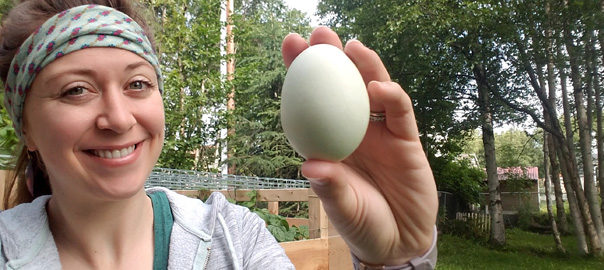 young woman holding colored chicken egg